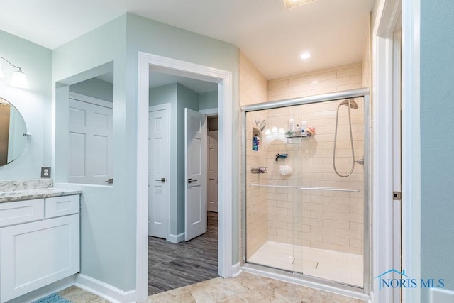 full bath featuring a shower stall, vanity, and baseboards