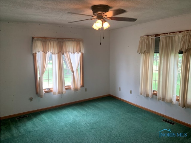 carpeted empty room with ceiling fan, a textured ceiling, and a healthy amount of sunlight