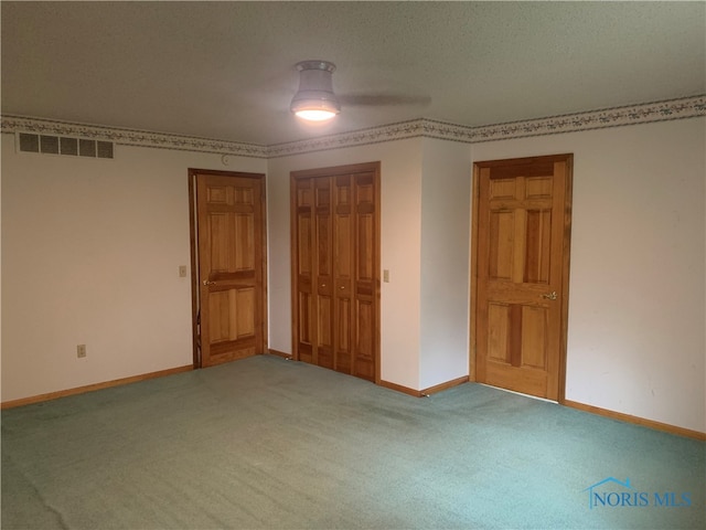 unfurnished bedroom featuring a textured ceiling, carpet, a closet, and ceiling fan