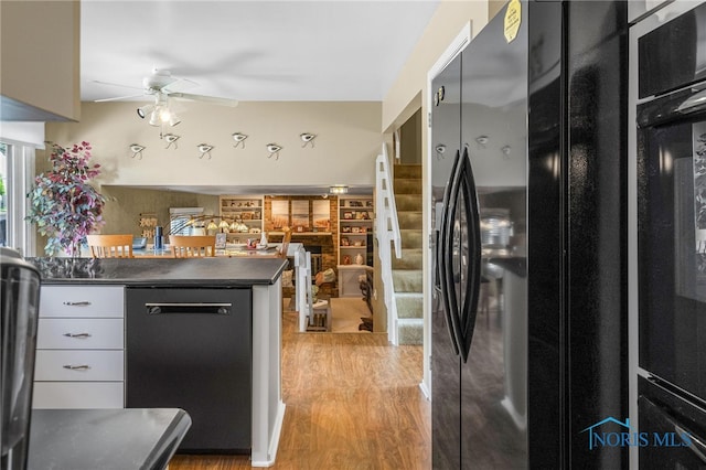 kitchen featuring black fridge with ice dispenser, light wood-type flooring, dishwasher, ceiling fan, and kitchen peninsula