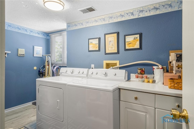 laundry room with a textured ceiling, cabinets, independent washer and dryer, and light hardwood / wood-style floors