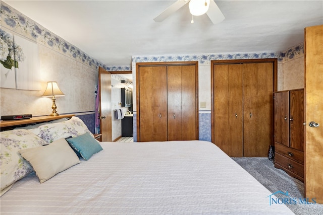 carpeted bedroom with ceiling fan and two closets