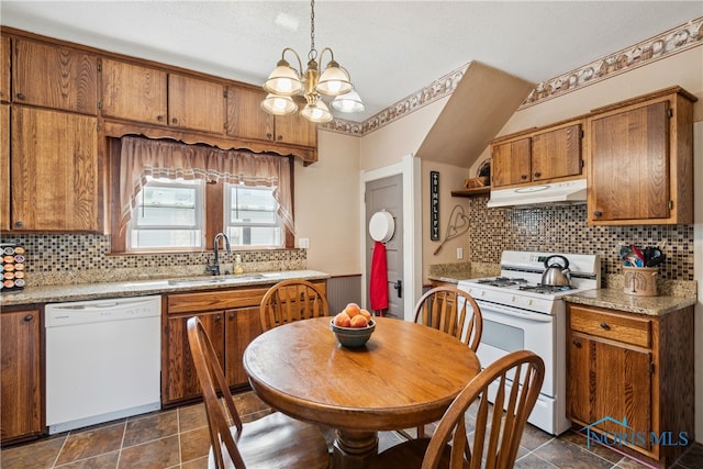 kitchen featuring backsplash, pendant lighting, a notable chandelier, dark tile patterned floors, and white appliances