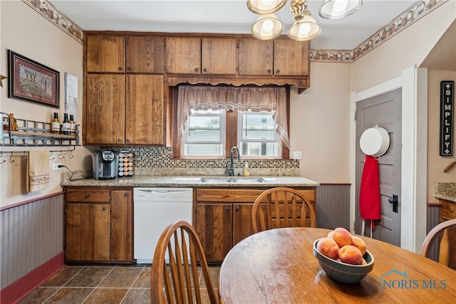 kitchen with sink, a notable chandelier, dark tile patterned flooring, white dishwasher, and tasteful backsplash