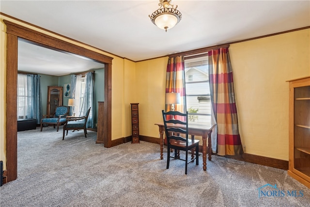 carpeted dining room with ornamental molding