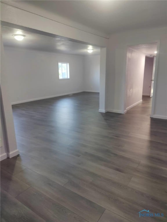 empty room featuring dark wood-style flooring and baseboards