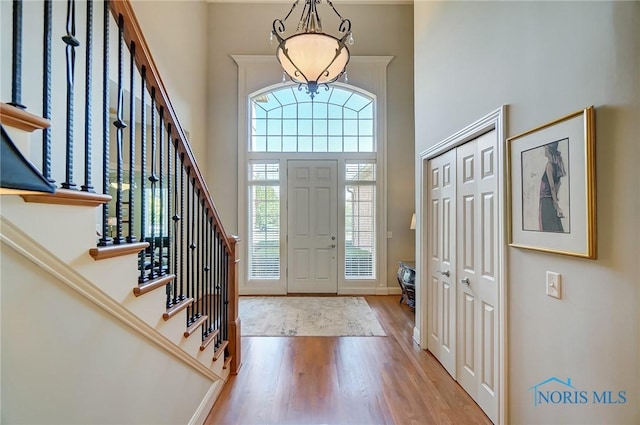 foyer featuring stairs, light wood finished floors, a high ceiling, and baseboards