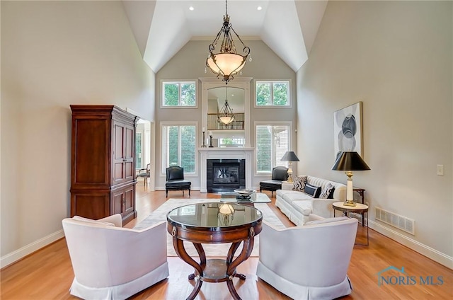 living area with baseboards, visible vents, light wood-style flooring, and a tiled fireplace