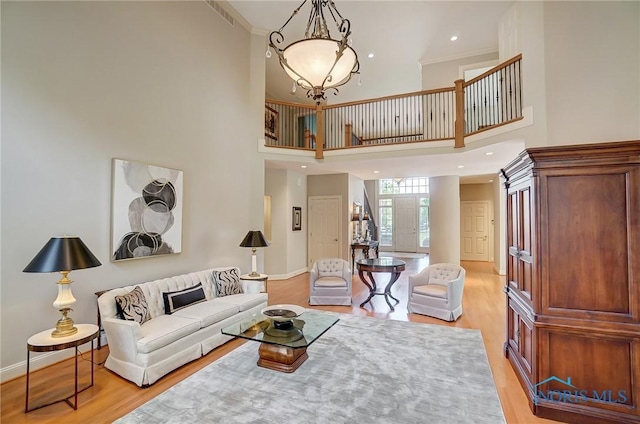 living room with baseboards, light wood finished floors, and crown molding