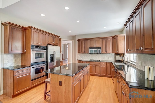 kitchen with stainless steel appliances, brown cabinetry, and a kitchen island