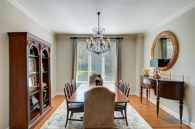 dining room with an inviting chandelier, light wood-style flooring, baseboards, and crown molding