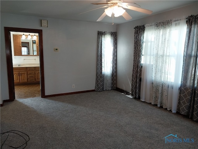 carpeted empty room with ceiling fan, sink, and a wealth of natural light