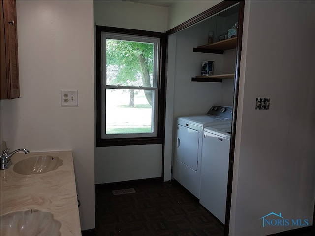 laundry room featuring independent washer and dryer, sink, dark parquet flooring, and plenty of natural light