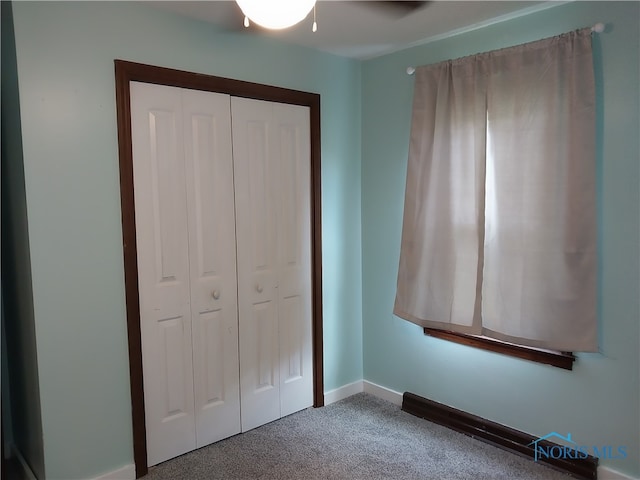 unfurnished bedroom with ceiling fan, a closet, and carpet