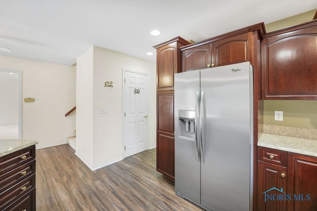 kitchen with stainless steel fridge, light stone counters, and dark hardwood / wood-style flooring