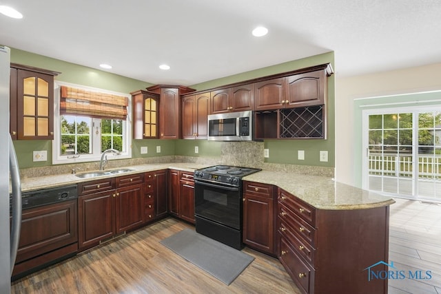 kitchen with sink, light hardwood / wood-style floors, light stone countertops, and stainless steel appliances