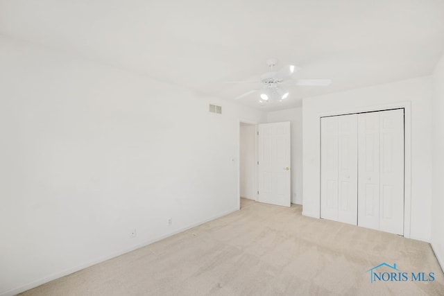 unfurnished bedroom featuring a closet, ceiling fan, and light colored carpet