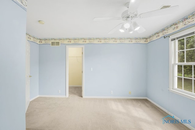 carpeted empty room with ceiling fan and a wealth of natural light