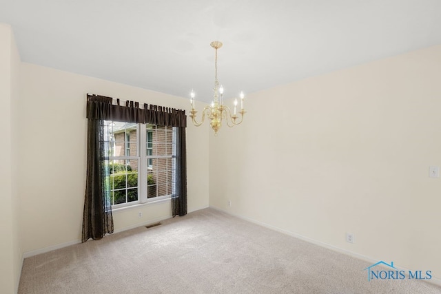 spare room featuring carpet floors and a chandelier