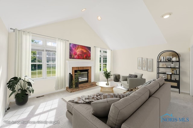 carpeted living room featuring a fireplace and high vaulted ceiling