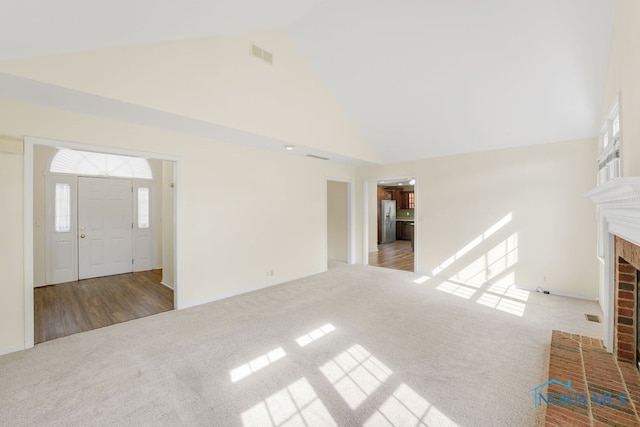 unfurnished living room featuring a fireplace, high vaulted ceiling, and carpet