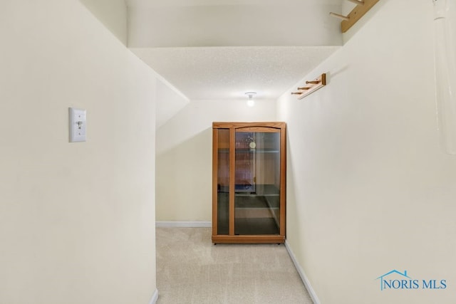 hallway featuring light carpet and a textured ceiling