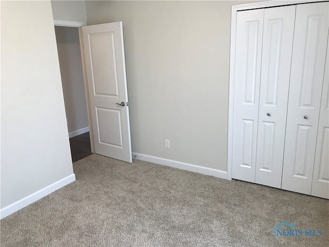 unfurnished bedroom featuring a closet and light colored carpet