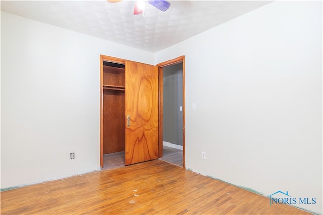 unfurnished bedroom with hardwood / wood-style flooring, a closet, and ceiling fan