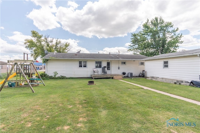 back of property featuring a playground, a yard, and a wooden deck