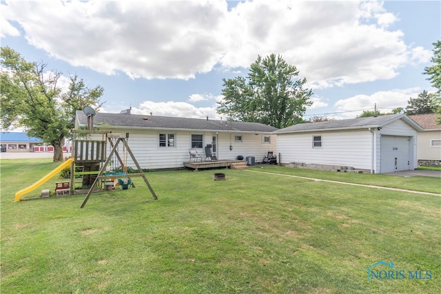 back of property featuring a garage, a playground, an outdoor structure, and a yard