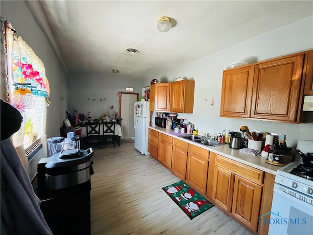 kitchen with ventilation hood, white appliances, light wood-type flooring, and sink