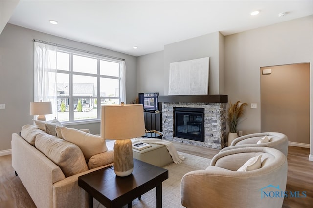 living room with a stone fireplace and light hardwood / wood-style floors