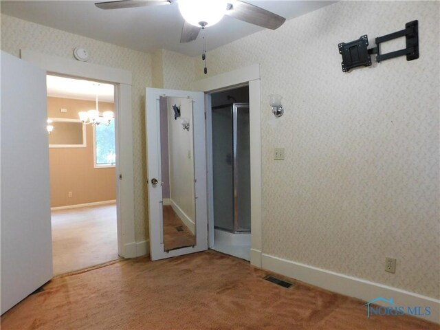 unfurnished bedroom featuring carpet and ceiling fan with notable chandelier