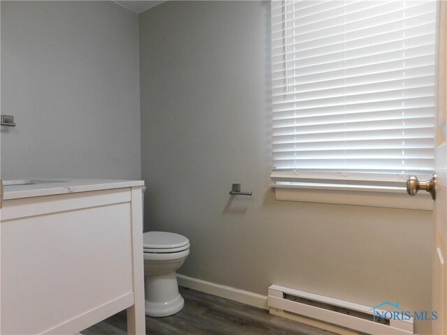 bathroom with toilet, hardwood / wood-style floors, a baseboard heating unit, and vanity