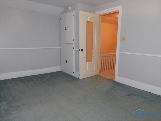 carpeted spare room with lofted ceiling