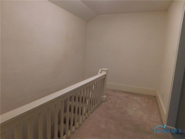 hallway with an upstairs landing, light carpet, baseboards, and lofted ceiling