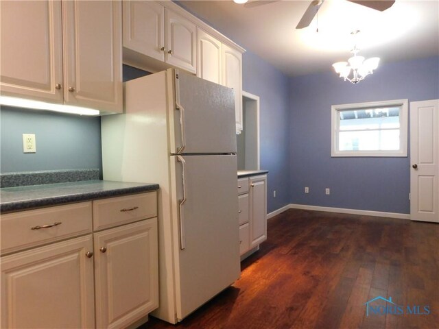 kitchen featuring dark hardwood / wood-style flooring, white fridge, ceiling fan with notable chandelier, white cabinetry, and hanging light fixtures