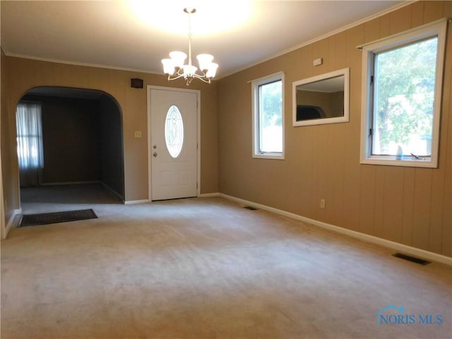 entryway with arched walkways, visible vents, carpet floors, and ornamental molding