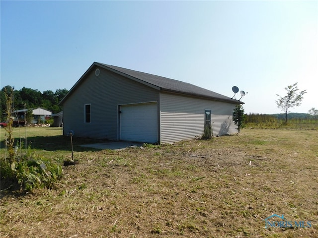 view of side of property featuring a lawn, an outdoor structure, and a garage