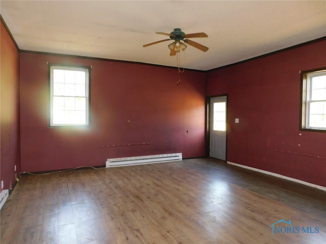 unfurnished room featuring baseboard heating, a healthy amount of sunlight, hardwood / wood-style floors, and ornamental molding