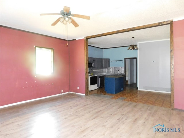 unfurnished living room with ceiling fan with notable chandelier and hardwood / wood-style flooring