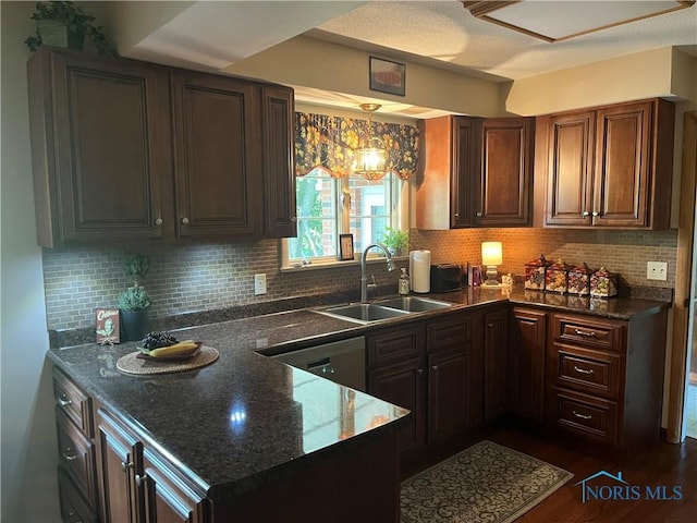 kitchen featuring dark wood-type flooring, sink, stainless steel dishwasher, decorative backsplash, and decorative light fixtures