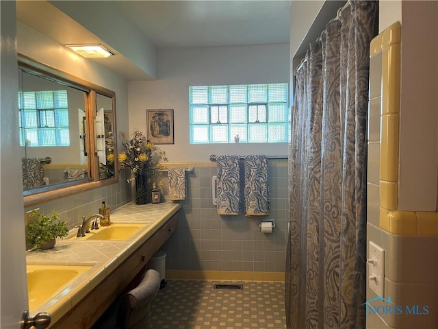 bathroom featuring tile patterned flooring, vanity, and tile walls