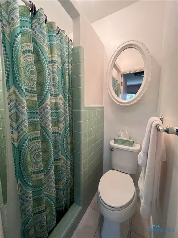 bathroom with tile patterned floors, curtained shower, and toilet