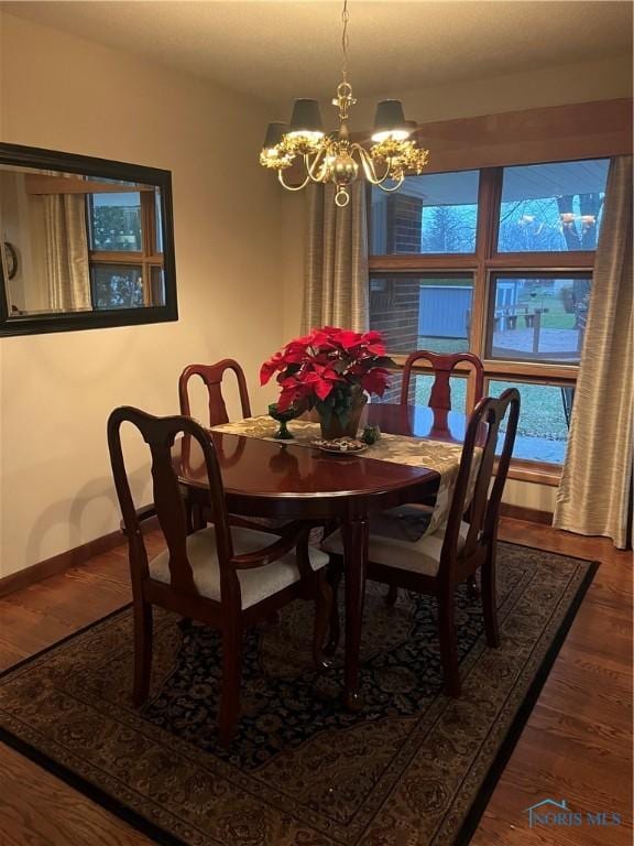 dining room with dark hardwood / wood-style flooring and an inviting chandelier