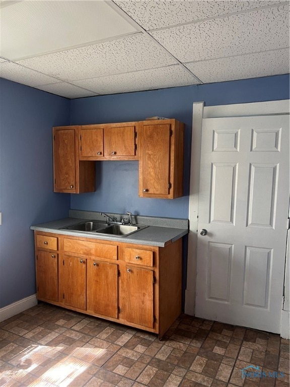 kitchen featuring a drop ceiling, sink, and dark tile patterned flooring