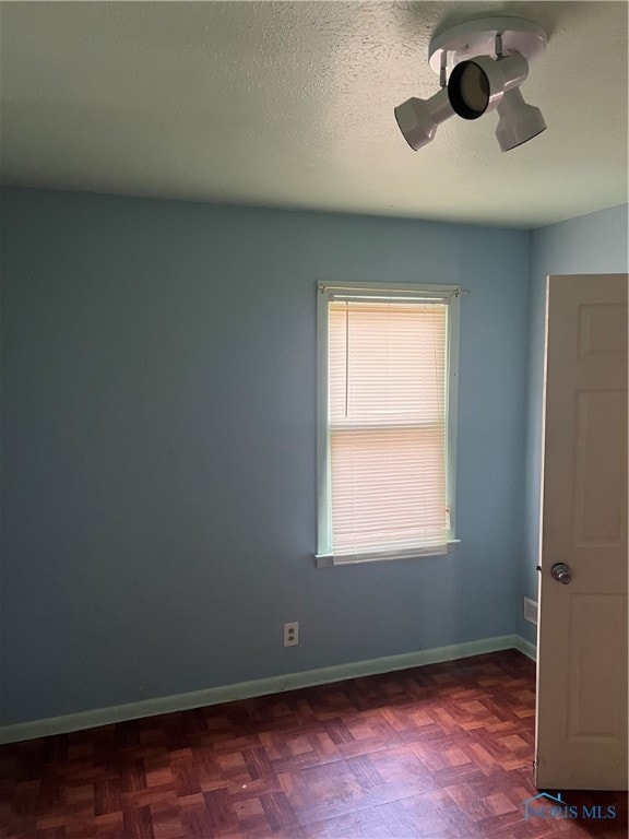 spare room with a textured ceiling and parquet floors