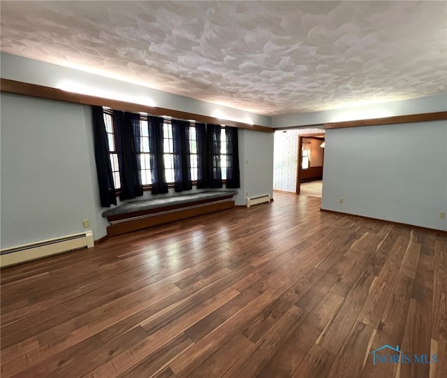 unfurnished living room featuring dark hardwood / wood-style flooring and a baseboard heating unit