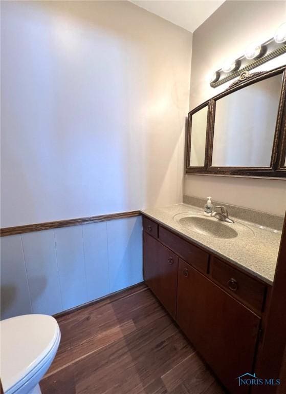 bathroom with wood-type flooring, toilet, and vanity