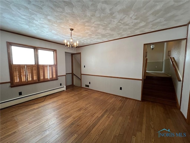 spare room with a baseboard radiator, wood-type flooring, and a notable chandelier